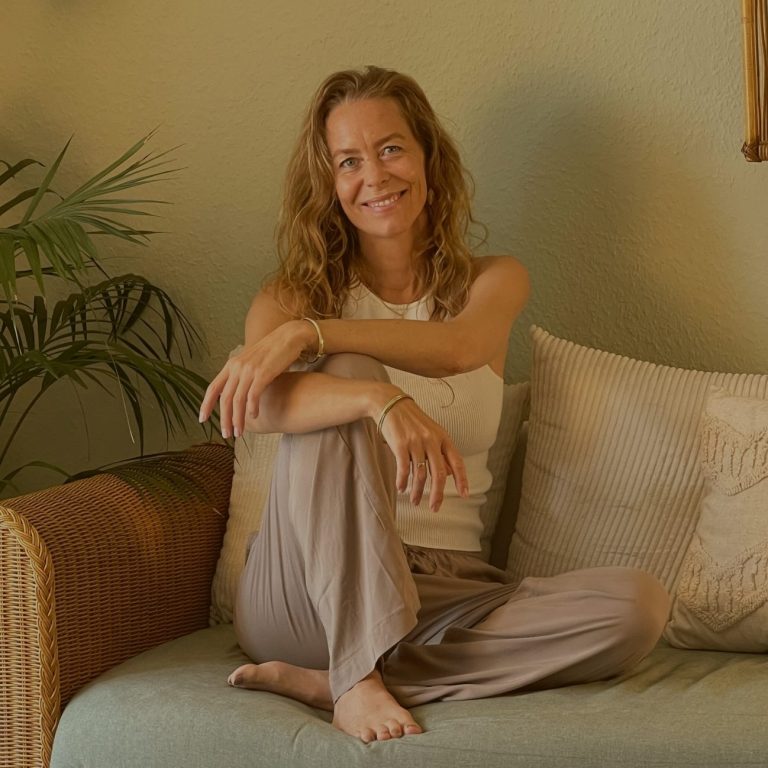 Svenja Eschenburg sitzt auf einem Sofa und lächelt in die Kamera.